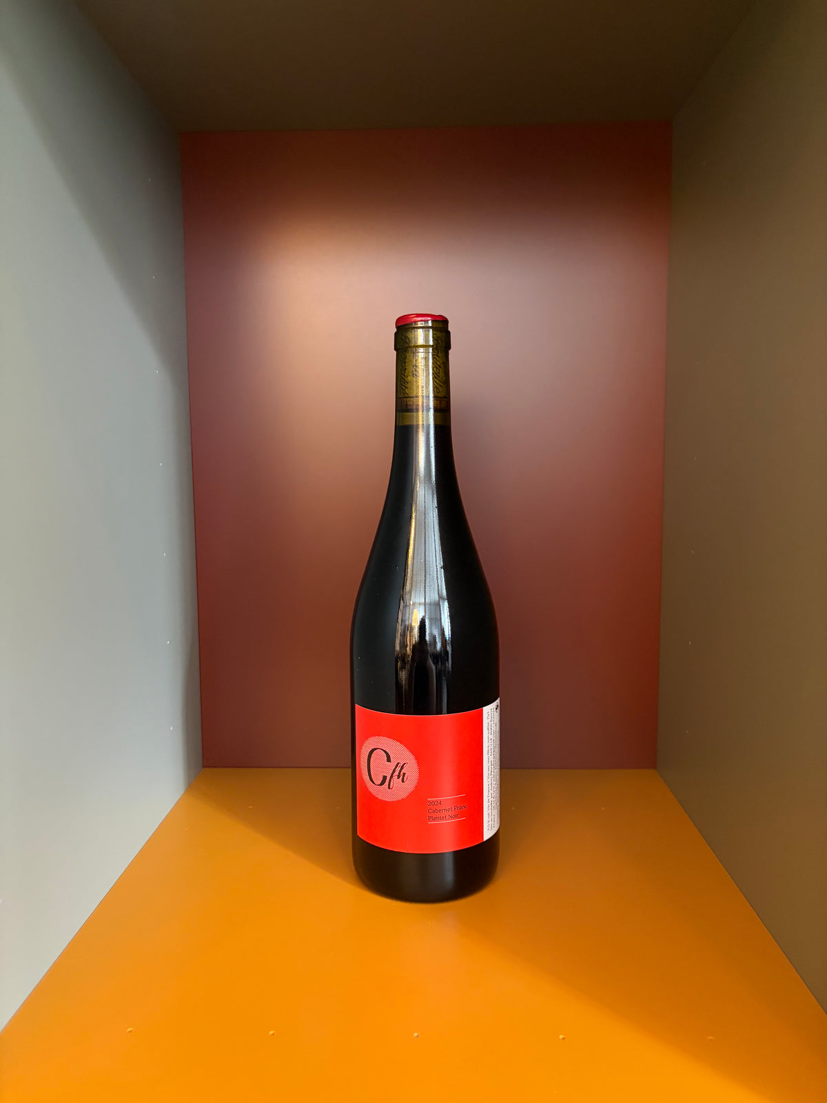 Wine bottle with dark glass and red front label, foil-lined neck and cap