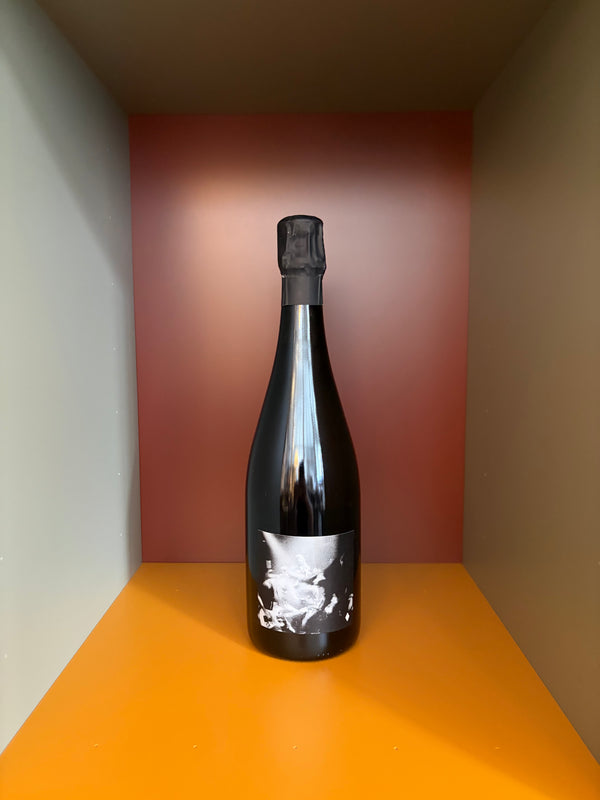 Sparkling wine bottle with dark foil cap and label featuring a white splash graphic
