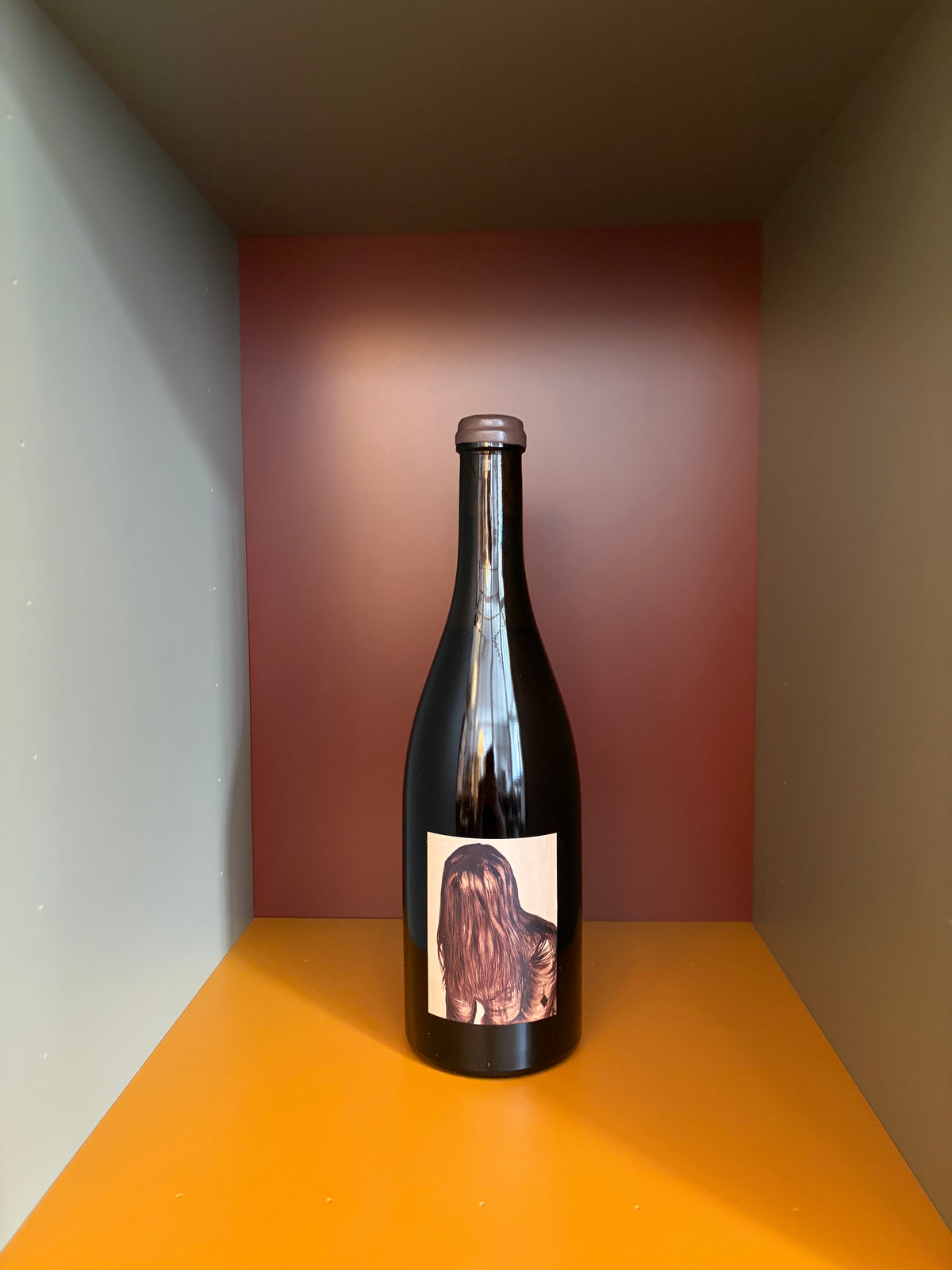 White wine bottle with dark glass, foil neck, and abstract pink label