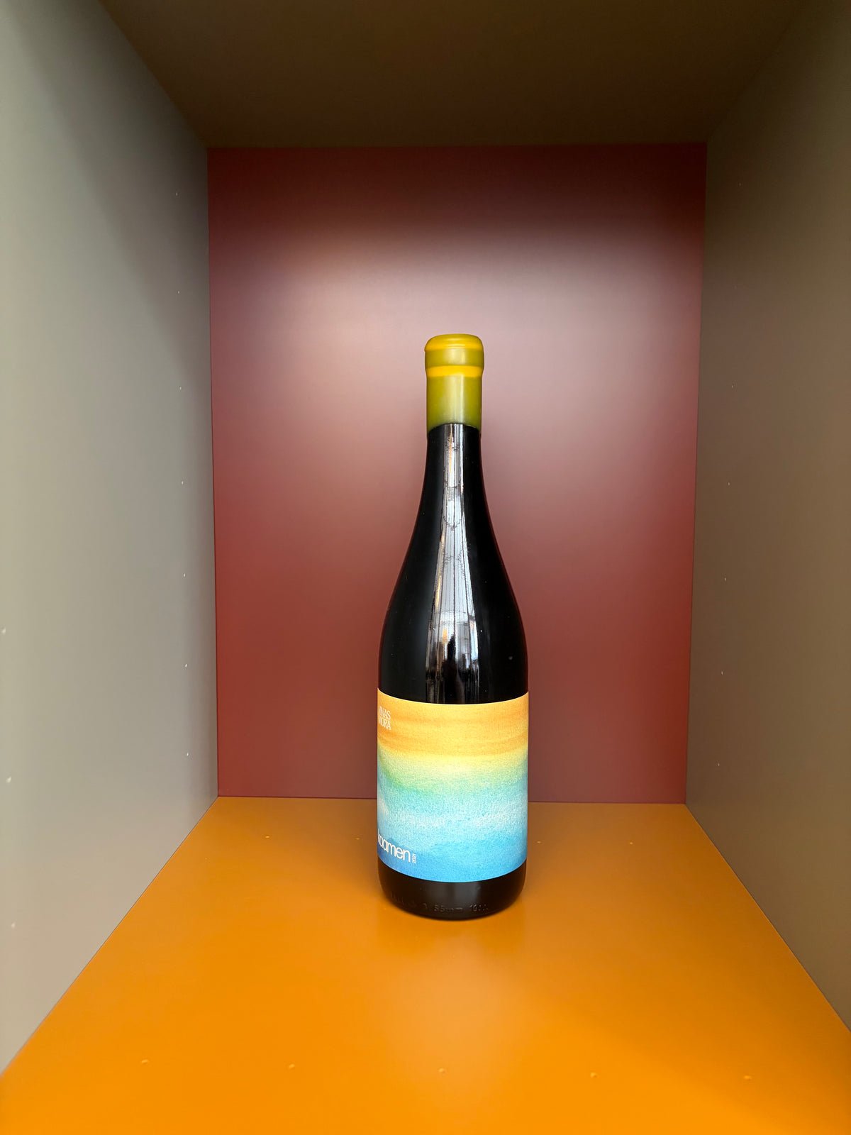 Wine bottle with dark glass and colorful blue-yellow label, yellow foil cap