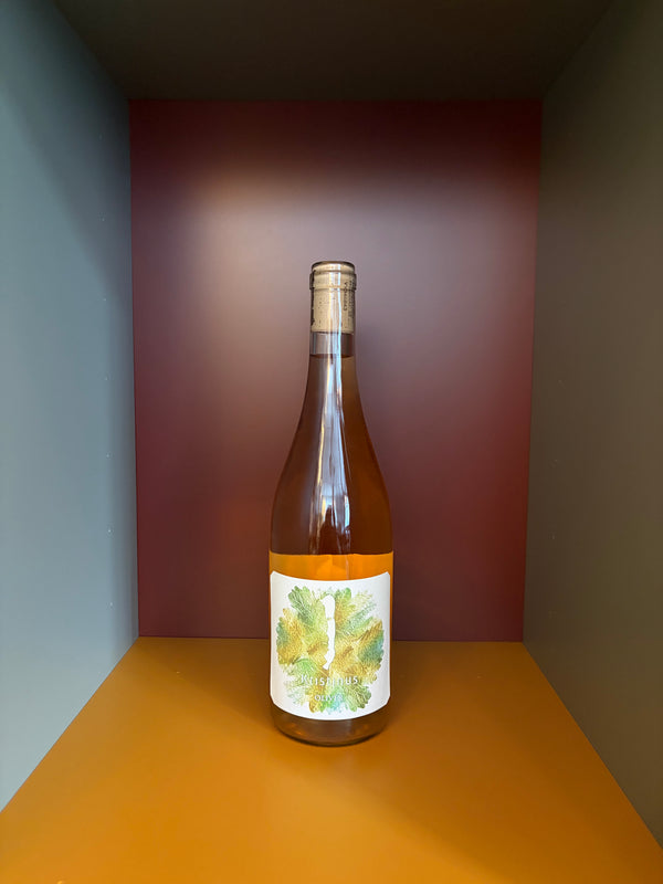 Wine bottle with pale gold liquid and white label with green leaf design